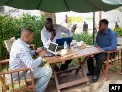FILE - Men work on their laptops at the Endiro Cade in Kampala, Uganda.
