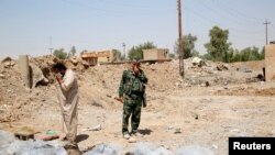 Dua warga Irak ini harus menutup hidung setelah menemukan kuburan massal ISIS di Irak utara (foto: dok).