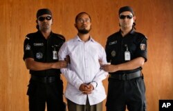 Members of Bangladesh’s Rapid Action Battalion (RAB) force escort Farabi Shafiur Rahman, center, a suspect in the murder of an American blogger Avijit Roy, during his presentation to the media in Dhaka, March 2, 2015.