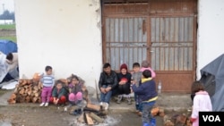Refugee family attempts to stay warm not far from Macedonian border, in Idomeni, Greece, March 16, 2016. (J. Dettmer/VOA)