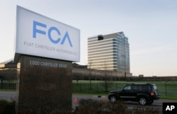 FILE - In this May 6, 2014, photo, a vehicle moves past a sign outside Fiat Chrysler Automobiles world headquarters in Auburn Hills, Michigan.