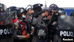 Seorang perwira polisi membidik senjata ke arah para pedemo yang memprotes kudeta militer dan menuntut pembebasan pemimpin Myanmar terpilih, Aung San Suu Kyii di Naypyitaw, Myanmar, 9 Februari 2021. (Foto: Stringer/Reuters)