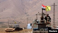 FILE - Hezbollah and Syrian flags flutter on a military vehicle in Western Qalamoun, Syria.