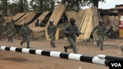 UPDF officers run towards a crowd that had assembled near Kasangati Police Station chanting "people power" slogans. Legislator Robert Kyagulanyi (aka Bobi Wine) was suspected to have been held at the Police station, in Kasangati, Uganda. (H. Athumani/VOA)