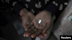 FILE - An HIV patient holds an anti-retroviral drug.