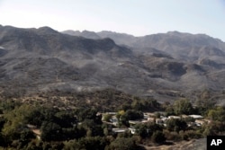 Burned down mountains tower over a residential neighborhood in the aftermath of a wildfire, Nov. 12, 2018, in Westlake Village, California.