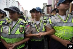 Bolivarian National Police officers lock arms, forming a human chain to block opposition marchers from reaching the National Electoral Council building in Caracas, Venezuela, July 27, 2016.