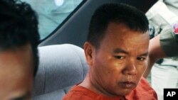 Yem Chrin, left, an unlicensed medical practitioner, sits in a car as escorting by prison guards after a verdict announcing of the Battambang provincial court in Battambang province, northwest of Phnom Penh, Cambodia, Thursday, Dec. 3, 2015. The Cambodian