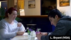 Salvation Army social worker Ludivine Colas handing small allowance to migrants.