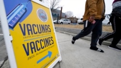 A sign, in Spanish and English, points the way to a vaccination clinic at City of Lawrence's "The Center," which serves seniors, families and the community, in Lawrence, Mass., Dec. 29, 2021.