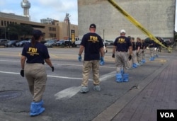 FBI investigators search for evidence in Thursday's sniper attack on police officers in downtown Dallas, Texas, July 9, 2016. (G. Tobias/VOA News)