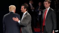 FILE - Donald Trump talks to his sons Donald Trump, Jr., and Eric Trump after the second presidential debate, Oct. 9, 2016.