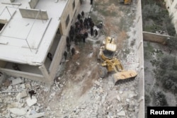 FILE - Civil defense workers remove dead bodies from under debris after an airstrike on Kafr Hamra village in the northern Aleppo countryside of Syria, Feb. 27, 2016.