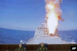 Colonel General Sergei Surovikin, commander of the Russian forces in Syria, left, and Colonel General Sergei Rudskoi of the Russian General Staff attend a briefing in the Russian Defense Ministry in Moscow, June 9, 2017. A screen in the back shows a Russian navy's Admiral Essen frigate launching a cruise missile at the Islamic State in Syria.
