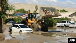 Bomberos de la comunidad de Cathedral City, California, rescatan a residentes en la pala de una topadora en medio de un lodazal dejado por el paso de la tormenta tropical Hilary el 21 de agosto de 2023.
