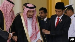 Indonesian President Joko Widodo (R) assists Saudi King Salman (C) as they walk during their meeting at the presidential palace in Bogor, West Java, Indonesia, March 1, 2017.