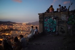 People gather outdoors at dusk on a viewpoint in Barcelona, Spain, July 25, 2020.