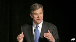 FILE - Roy Cooper speaks during a forum in Charlotte, N.C.
