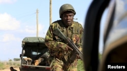 FILE - A Kenya Defense Force soldier runs for cover near the perimeter wall where al-Shabab attackers have holed up at a campus in Garissa, Kenya, April 2, 2015. 