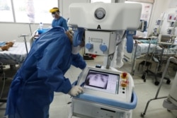 A healthcare worker wearing full protective gear looks at the chest X-ray of a patient in a ward reserved for COVID-19 patients at the Hospital Juarez, in Mexico City, June 26, 2020.