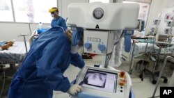 A health care worker wearing full protective gear looks at the chest X-ray of a patient in a ward reserved for COVID-19 patients at the Hospital Juarez, in Mexico City, June 26, 2020.