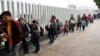 FILE - People line up to cross into the United States to begin the process of applying for asylum near the San Ysidro port of entry in Tijuana, Mexico, July 26, 2018. 