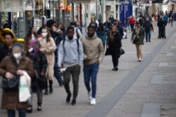 FILE - People walk along a shopping street as stores reopened after lockdown was loosened during the coronavirus pandemic in Vienna, Austria, May 3, 2021.