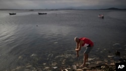 FILE - A man washes himself in the polluted waters of Guanabara Bay in Rio de Janeiro, Brazil, July 30, 2016. 