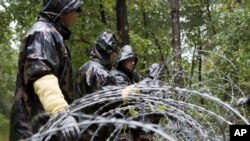 FILE - Hungarian soldiers put up spools of razor wire on Slovenian border in Zitkovci, Sept. 25, 2015. Hungary installed spools of razor wire near a border crossing with Slovenia, which like Hungary is part of the EU's Schengen zone of passport-free travel.
