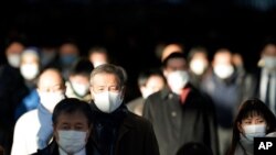 A station passageway is crowded with commuters wearing face masks during rush hour, Jan. 8, 2021, in Tokyo.