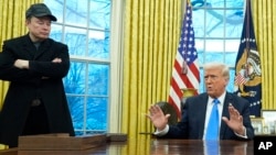 President Donald Trump speaks with reporters as Elon Musk listens in the Oval Office at the White House, Feb. 11, 2025, in Washington. 