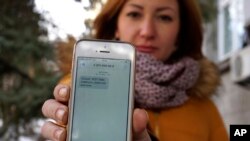 FILE - Television journalist Julia Kirienko holds up her smartphone to show a text message reading “Ukrainian soldiers, they’ll find your bodies when the snow melts,” in Kyiv, Ukraine, Feb. 22, 2017.