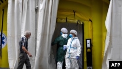 FILE - Health care workers wearing protective gear wait outside a field hospital set up for coronavirus cases outside the CAP Prat de la Riba primary care center in Lleida, July 13, 2020.