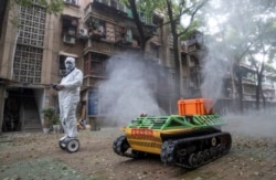 A volunteer operates a remote controlled robot to disinfect a residential area amid the COVID-19 outbreak in Wuhan in China's central Hubei province.