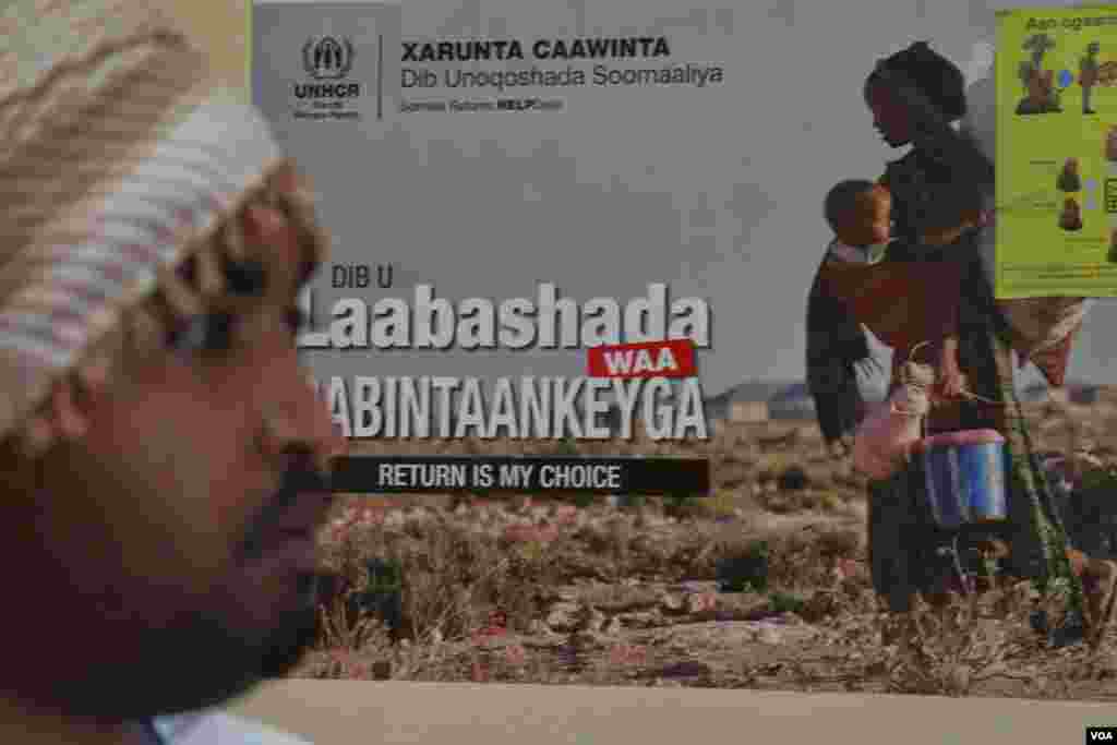 A UNHCR repatriation representative stands in front of a poster which reads 'Return Is My Choice,' Dadaab, Kenya, April 24, 2015. (Mohammed Yusuf/VOA)