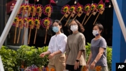 戴着口罩的行人走过北京街头一个售卖传统风车玩具的商铺。（2022年9月13日）