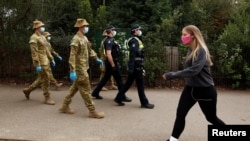 ADF personnel and Victorian police officers patrol a walking track as Melbourne remains in lockdown restrictions, In Melbourne, Australia, July 26, 2020. (AAP Image/Daniel Pockett via Reuters) 