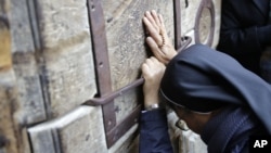 A woman prays outside the closed doors of the Church of the Holy Sepulcher, traditionally believed by many Christians to be the site of the crucifixion and burial of Jesus Christ, in Jerusalem, Feb. 27, 2018. 