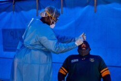 FILE - A member of South Sudanese Ministry of Health's Rapid Response Team take a sample from a man who had recently been in contact with a confirmed case of the COVID-19 coronavirus in Juba, South Sudan, April 13, 2020.