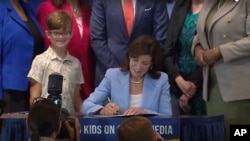 En esta imagen tomada de un video de la Oficina de la Gobernadora de Nueva York, Kathy Hochul firma el proyecto de ley que permitiría a los padres bloquear los feeds adictivos en redes sociales, el jueves 20 de junio de 2024. 