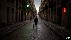 A man walks along an empty street in downtown Barcelona, Spain, March 26, 2020 as the lockdown to combat the spread of coronavirus continues. 