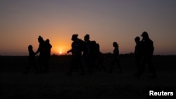 FILE - Migrants from Honduras and El Salvador walk towards the border wall after crossing the Rio Grande River into the United States from Mexico on a raft, in Penitas, Texas, March 26, 2021. 