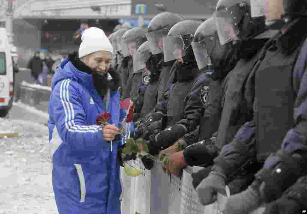A pro-European Union activist gives flowers to riot police on a main street in central Kyiv, Dec. 10, 2013.