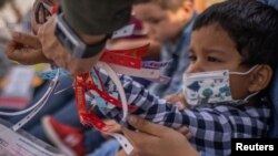 A U.S. Border Patrol Agent removes a wristband from Santiago, a 4-year-old asylum-seeking migrant boy from Honduras, after he crossed the Rio Grande River into the U.S. from Mexico with his mother, in Penitas, Texas, March 9, 2021.