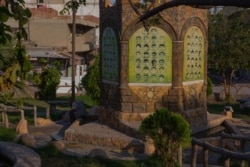 A man sits at a garden memorializing deceased Kurdish fighters in Dirik, Syria, Oct. 23, 2019. (Yan Boechat/VOA)