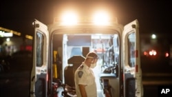 An EMT pauses while loading a stretcher back into an ambulance after dropping off a patient at a newly opened field hospital operated by Care New England for COVID-19 patients in Cranston, R.I, Dec. 1, 2020. 