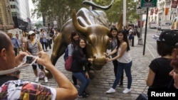 资料照：中国游客在纽约华尔街的铜牛前合影。（2015年8月24日）