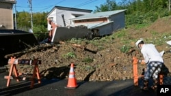 A worker places a barricade at a landslide in Hamamatsu of the Shizuoka prefecture, Japan, Sept. 24, 2022. Rain from Tropical Depression Talas set off landslides, halted trains and caused a fatal car crash.
