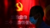A man wearing a face mask walks by a propaganda poster welcoming the 20th party congress, along a street in Beijing, Sept. 20, 2022. 