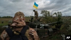 A Ukrainian national guard serviceman stands atop a destroyed Russian tank in an area near the border with Russia, in Kharkiv region, Ukraine, Sept. 19, 2022.